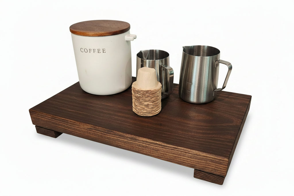 Wooden tray with coffee canister, milk bottle, and metal cups on a white background.