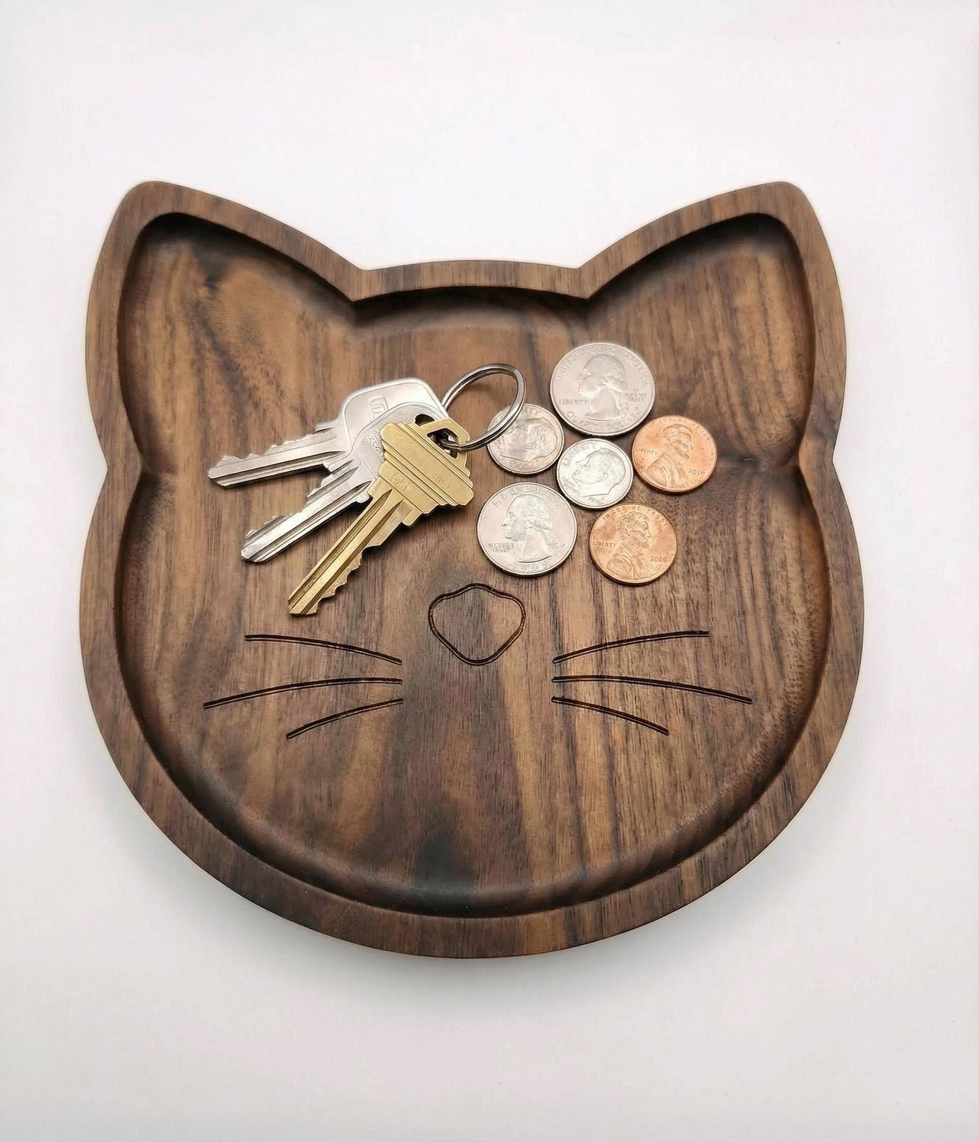 Wooden cat-shaped tray with keys and coins on a white background